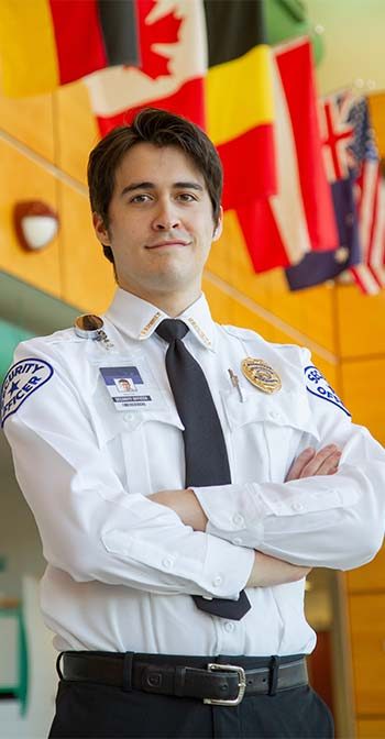 Security guard standing in a building with multiple country flags above him