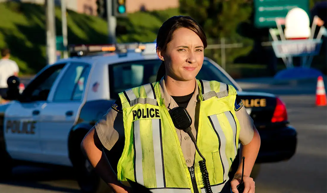 female police officer standing in front of a patrol car