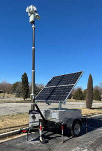 Solar-powered mobile surveillance trailer equipped with mounted cameras and floodlights