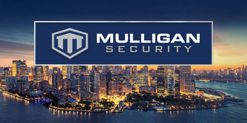 New York City skyline with skyscrapers lit up against a sunset sky, overlaid with the Mulligan Security logo