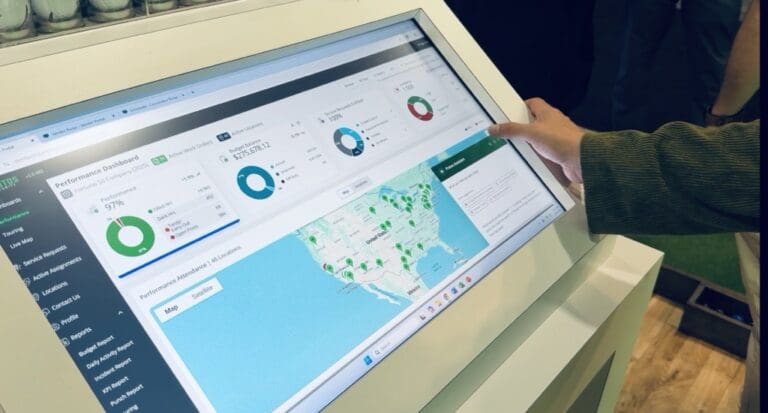A person interacts with a large touchscreen dashboard displaying performance metrics on client portal